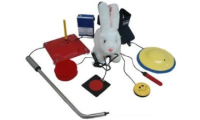 Herramientas de apoyo para controlar equipo electrónico, como botones y pedales, junto a un juguete de un conejo sobre una mesa blanca. 