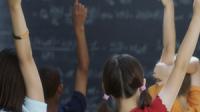 Niñas y niños en un salón de clase levantan la mano para participar