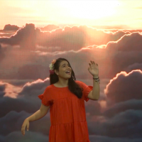 Cantautora: Massiel Rodríguez, cantando y con un fondo de un cielo con sol