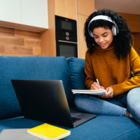 Adolescente sentada en un sillón y utilizando una laptop.