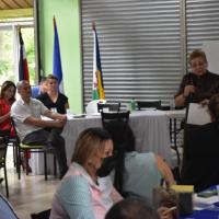 Personas escuchan palabras de la ministra, que está de pie al lado de una pizarr