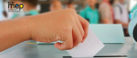 Mano de una persona estudiante votando en el aula