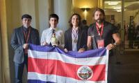 Estudiantes y profesores posan sonrientes con una bandera de Costa Rica que contiene un escudo del país