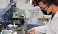 Estudiante masculino con gabacha blanca utiliza equipo de un laboratorio