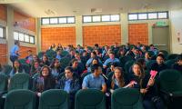 Estudiantes esperan el inicio de una actividad en las butacas de un auditorio