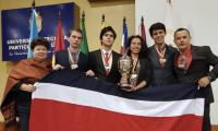Estudiantes galardonados con medallas y un trofeo posan sonrientes con una bandera de Costa Rica junto a sus profesores