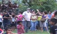 Señor de barba blanca sostiene el brazo de una mujer mientras explica a un grupo de personas