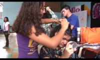 Mujer jóven le corta el cabello a otra mujer 