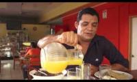 Hombre sirve un refresco de un pichel a un vaso en una mesa