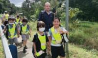 Niños y niñas caminando por la acera con sus chalecos reflectivos
