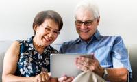 Una pareja de adultos mayores tiene una tablet en la mano.