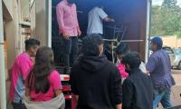 Estudiantes ayudan a descargar mobiliario donado de un camión 
