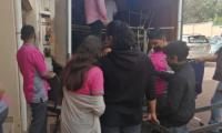 Un grupo de estudiantes esperan descargo de mobiliario donado a su institución