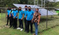 Estudiantes y una docente muestran uno de los paneles solares 
