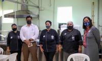 Cinco personas posan y como fondo una cocina industrial.