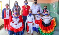 Aparece un grupo de personas posando para una foto. Niños se lucen con trajes