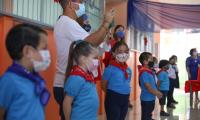 Niños y niñas de preescolar en una fila con su maestra. Todos portan mascarilla.