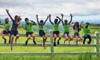 Grupo de estudiantes comparten sobre cerca de madera al aire libre 