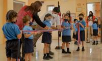 Niños sostienen una cinta de colores de la bandera y Presidente se encuentra ahí