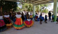 Niñas y niños vestidos con atuendos típicos.Al otro lado, niñas y niños pequeños