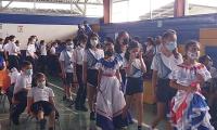Niñas y niños observando al frente. Algunas niñas portan vestidos típicos
